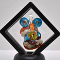 Colorful glass pendant with intricate designs on a black stand against a white background
