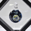 Glass pendant on a white surface with a black border