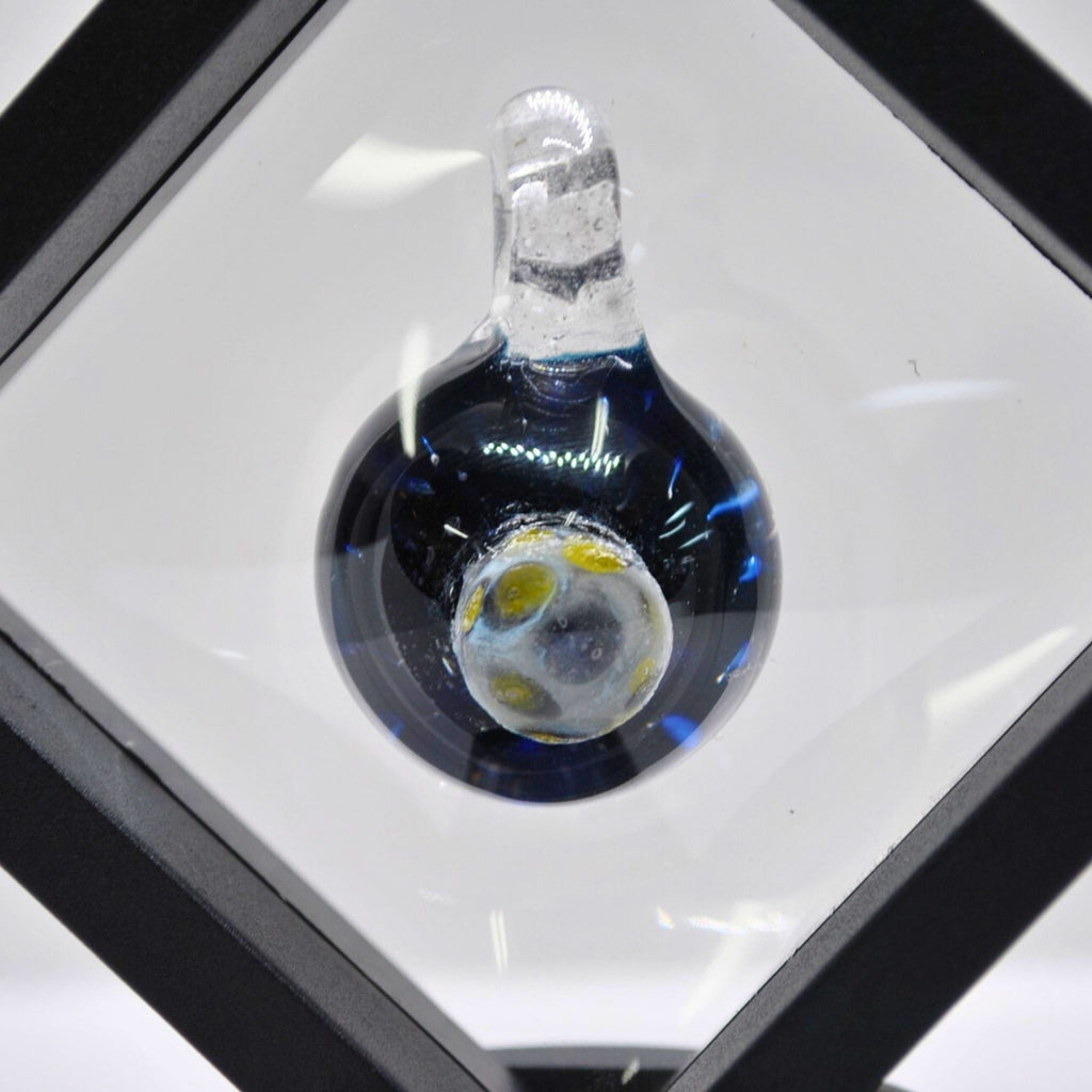 Glass pendant on a white surface with a black border