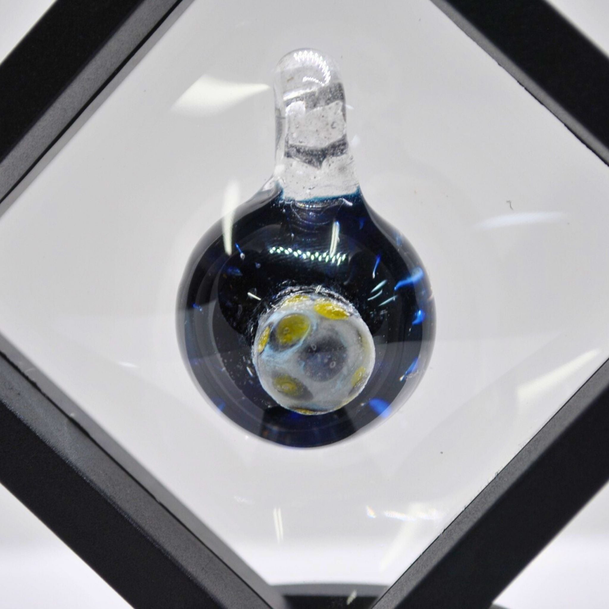 Glass pendant on a white surface with a black border