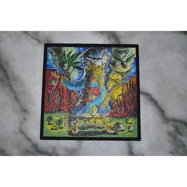 A square embroidered patch with a colorful fantasy illustration of a blue rooster with a yellow bill , bordered in black, displayed on a gray marble surface.