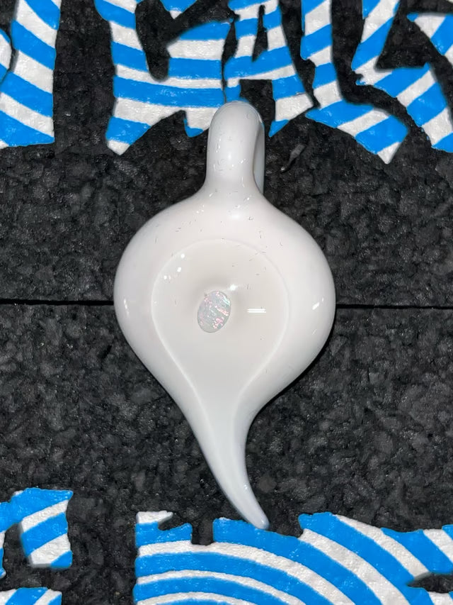 A glossy white Glass teardrop-shaped Pendant with a small loop at the top, resting on a textured black surface