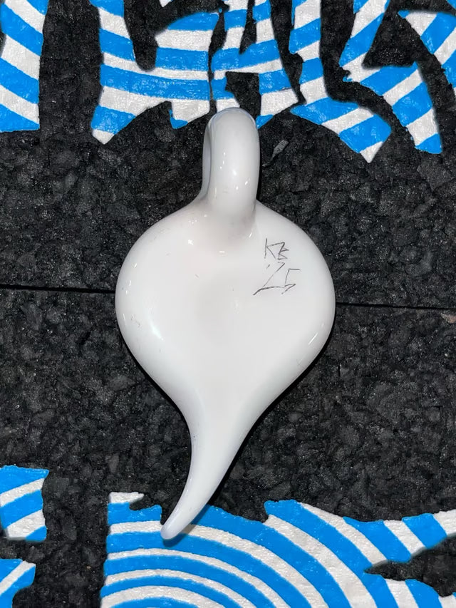 A glossy white Glass teardrop-shaped Pendant with a small loop at the top, resting on a textured black surface