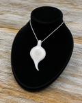 A glossy white Glass teardrop-shaped Pendant with a small loop at the top, resting on a textured black surface on a bust