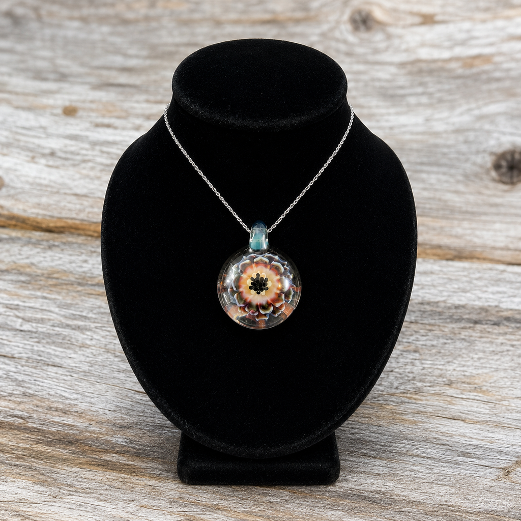 A silver chain necklace with a round glass pendant featuring a colorful floral design, displayed on a black velvet jewelry bust over a rustic wooden surface.